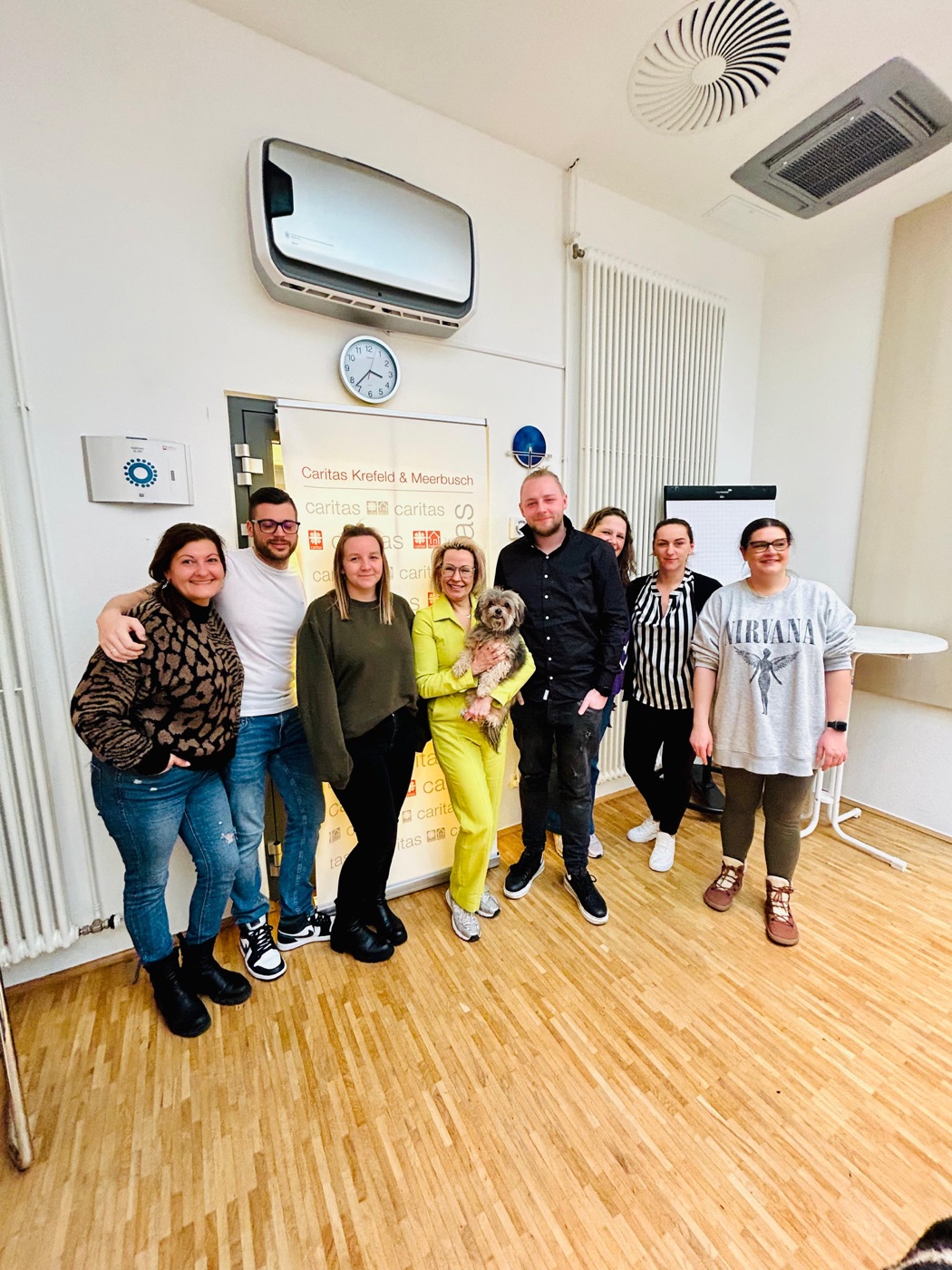 Seminargruppe des Caritasverbands Krefeld und Meerbusch vor dem Verbandsbanner